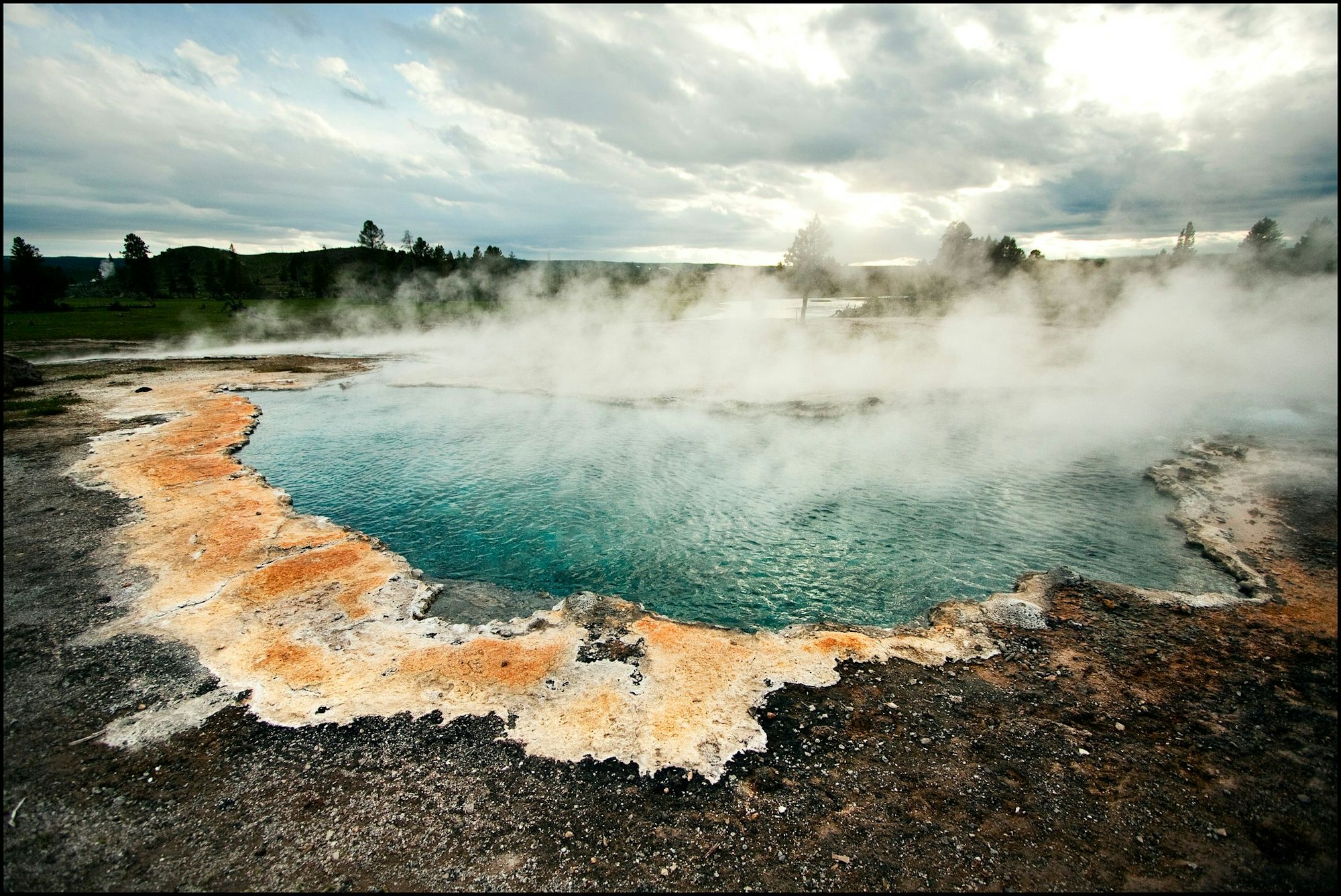 Von einer heißen Quelle steigt Dunst auf.