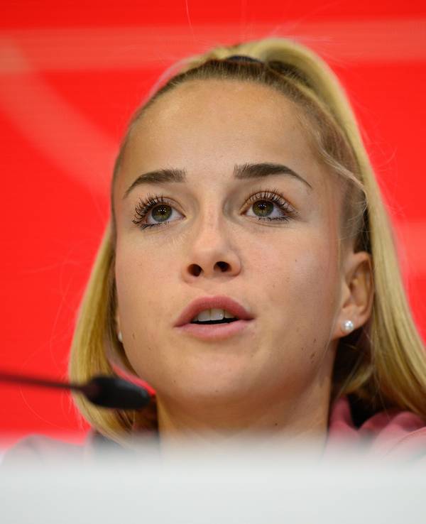 Giulia Gwinn sitzt bei einer Pressekonferenz auf dem Podium.