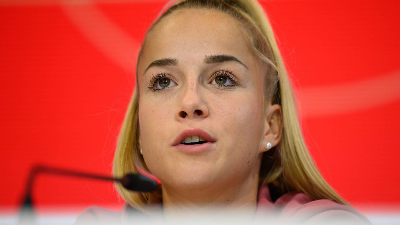 Giulia Gwinn sitzt bei einer Pressekonferenz auf dem Podium.