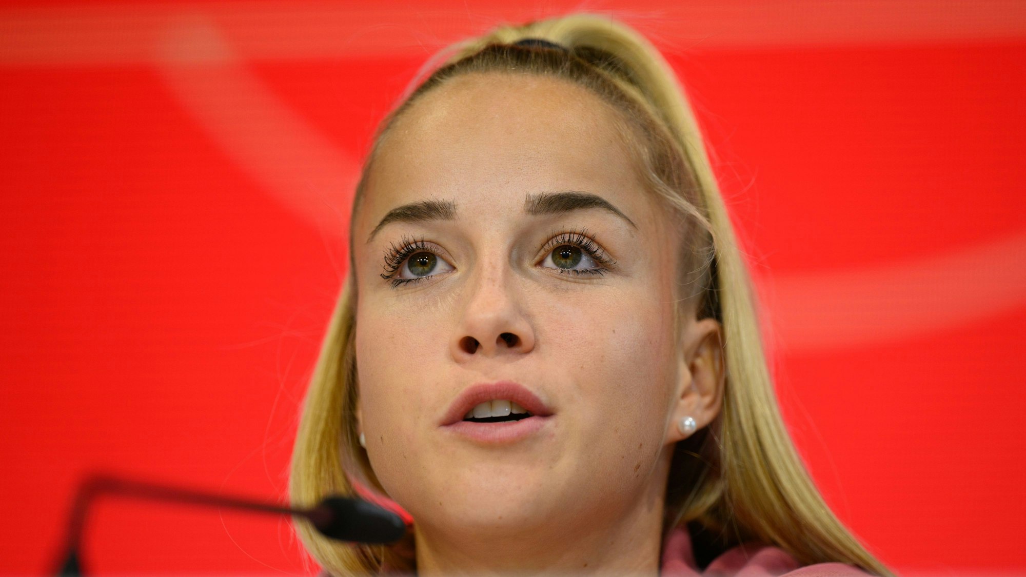Giulia Gwinn sitzt bei einer Pressekonferenz auf dem Podium.
