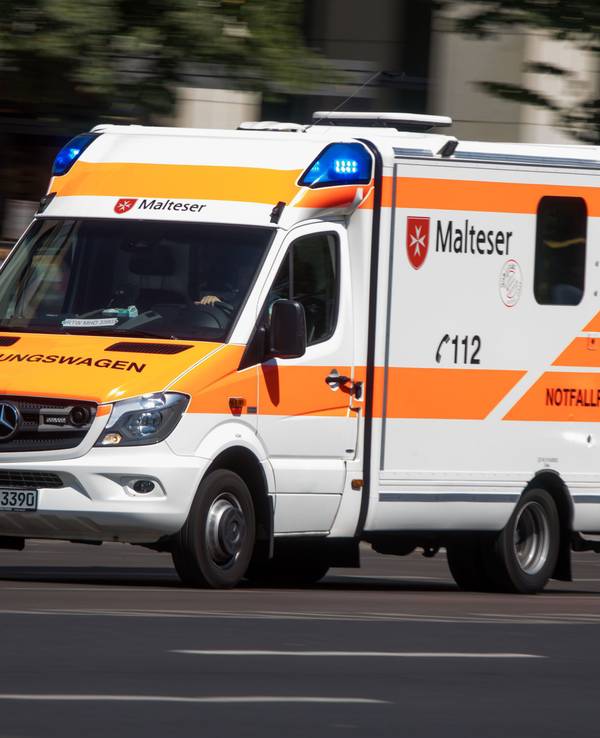 Rettungswagen mit Blaulicht auf einer Straße.