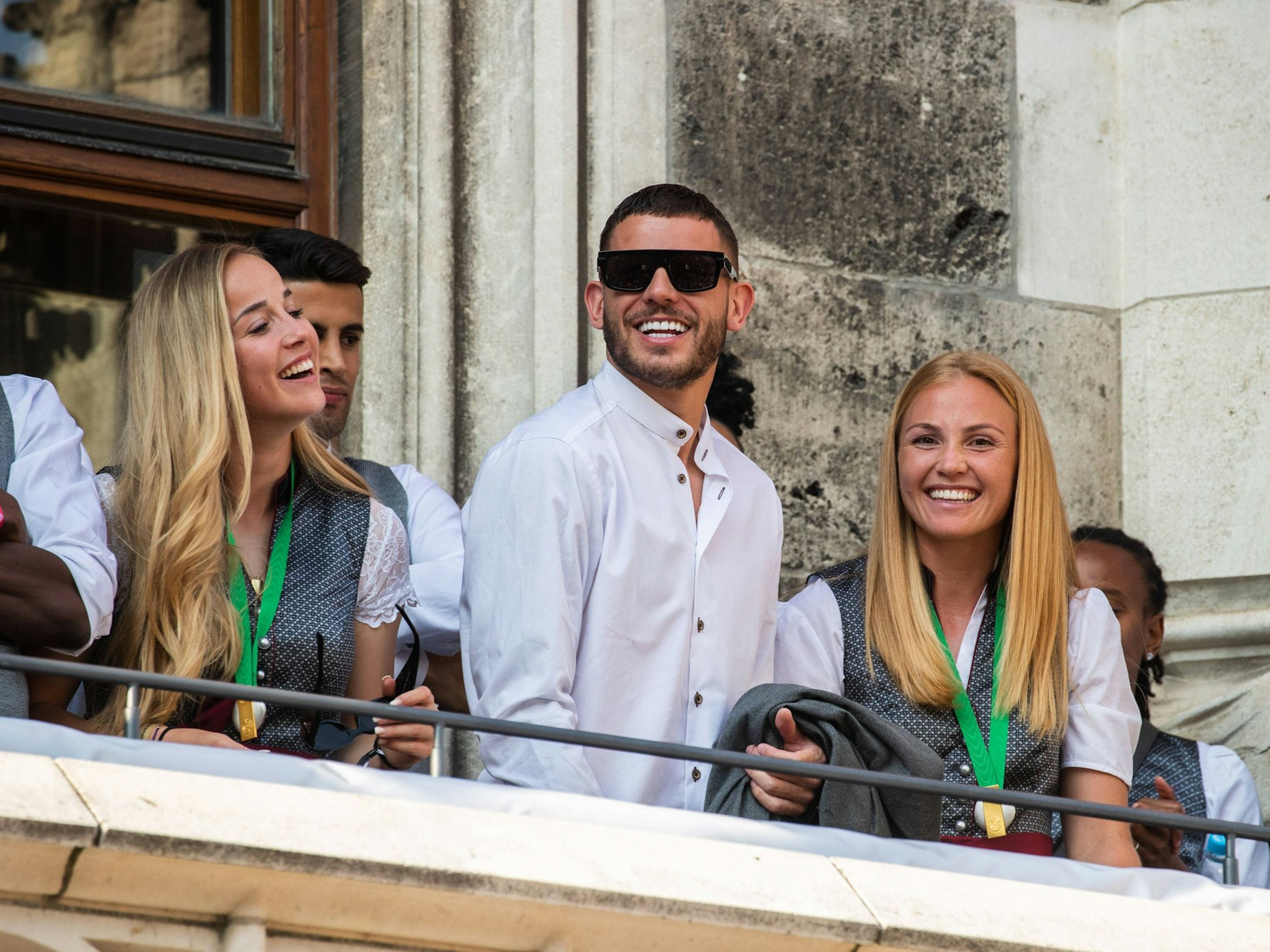 Lucas Hernandez steht bei der Meisterfeier des FC Bayern auf dem Rathausbalkon zwischen Giulia Gwinn (l.) und Glodis Viggosdottir.
