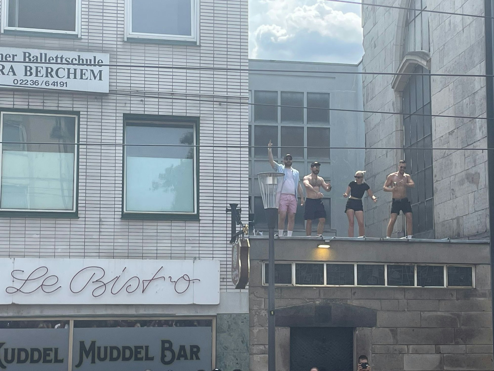 Bester Blick auf den Demo-Zug in Köln – vier CSD-Fans feiern auf einem Vordach