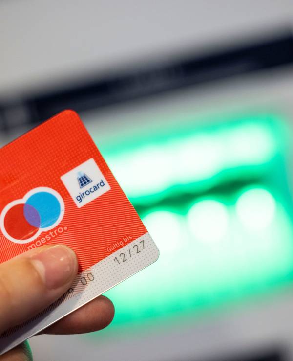 Eine Bankkundin verwendet ihre Girokarte, auf der das Girocard-Logo und das rot-blaue Maestro-Logo abgebildet sind, um Bargeld an einem Geldautomaten abzuheben, hier im Juni 2023.