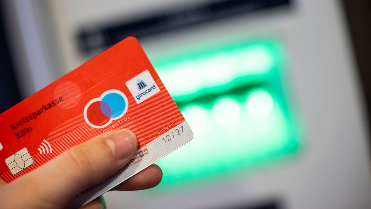 Eine Bankkundin verwendet ihre Girokarte, auf der das Girocard-Logo und das rot-blaue Maestro-Logo abgebildet sind, um Bargeld an einem Geldautomaten abzuheben, hier im Juni 2023.