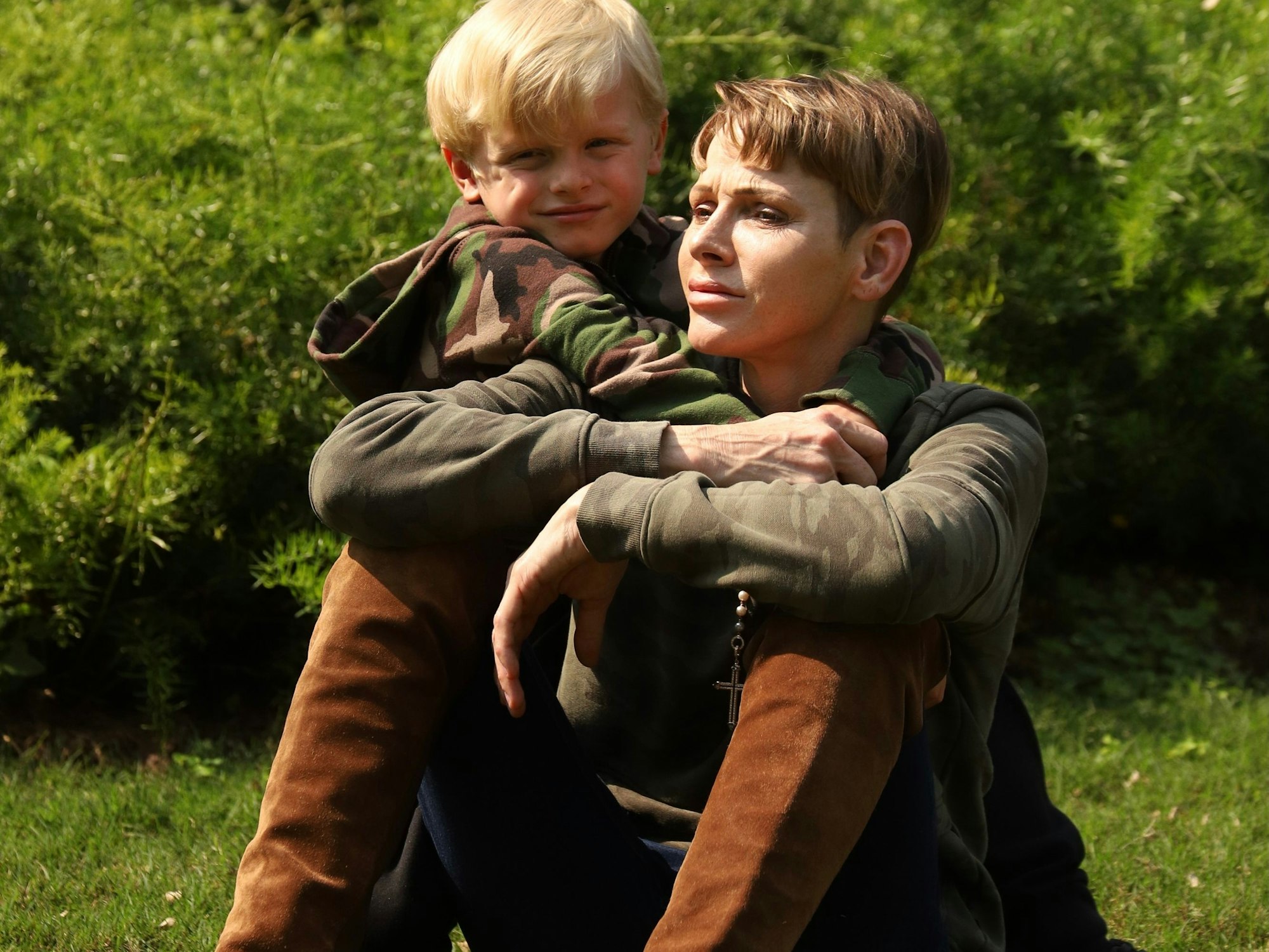 Fürstin Charlène von Monaco und ihr Sohn Jacques sitzen in einem Garten.