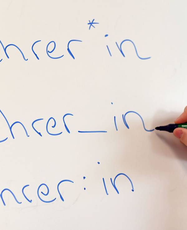 An einem Whiteboard steht das Wort „Lehrer“ in drei verschiedenen Gender-Schreibweisen.