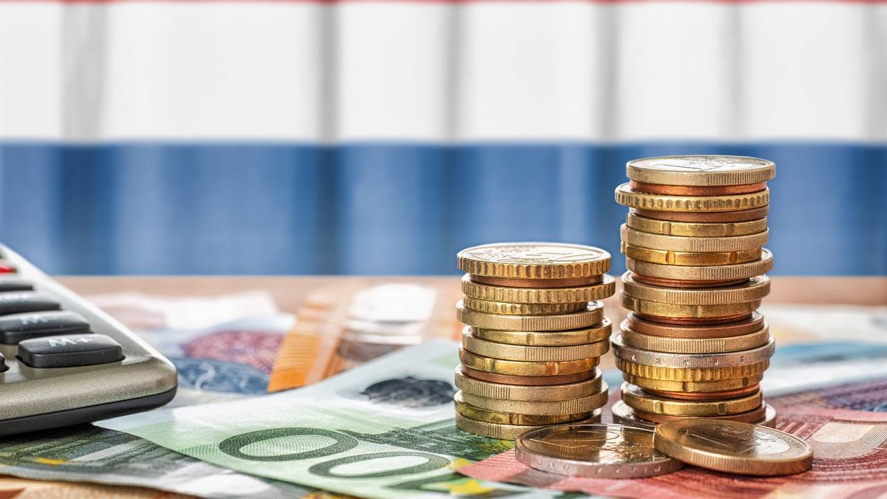 Euro Banknoten und Münzen liegen vor der niederländischen Flagge.