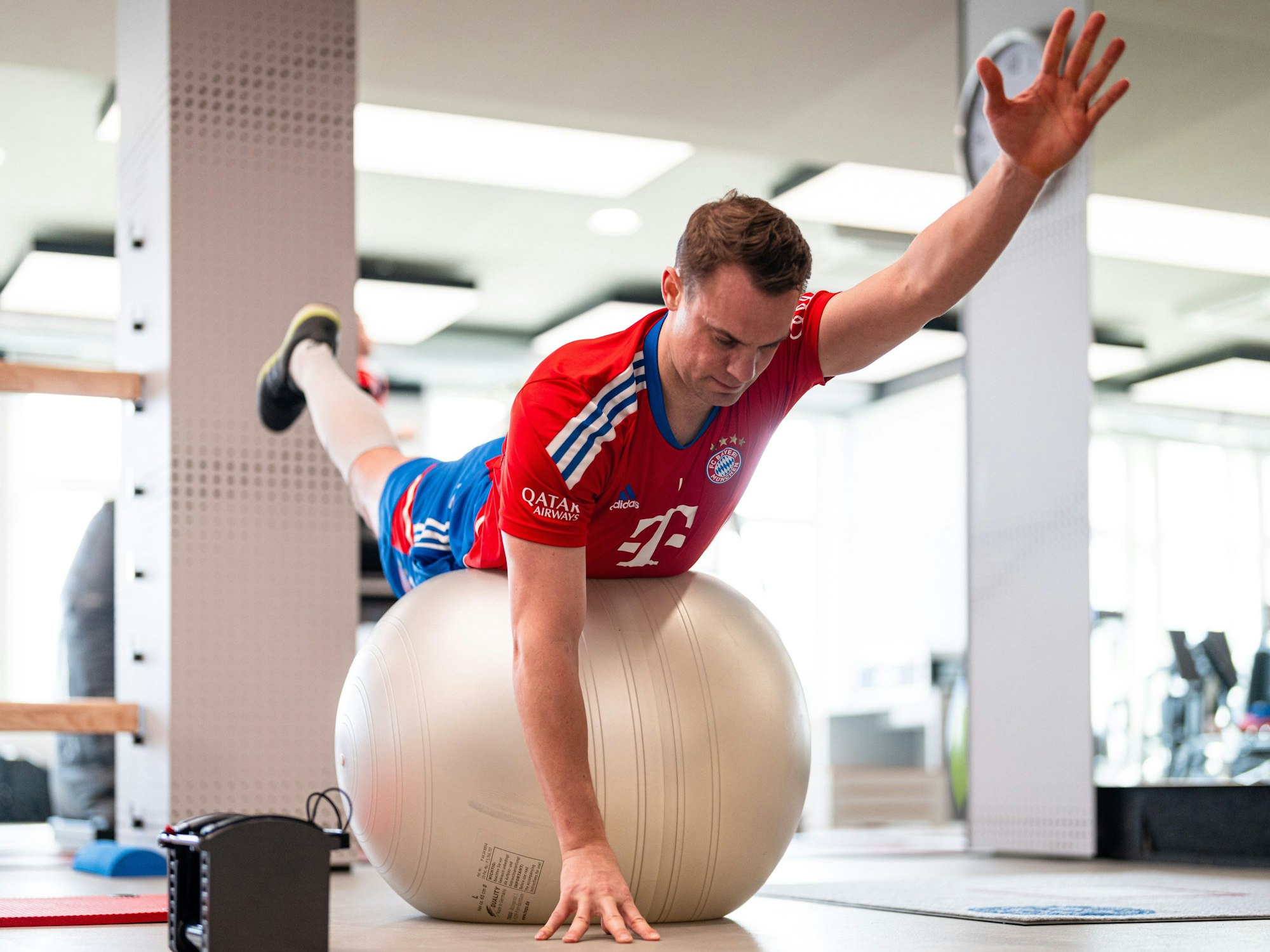 Manuel Neuer liegt mit dem Bauch auf einem Gymnastik-Ball und streckt die Gliedmaßen von sich.