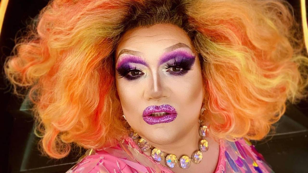 Die Dragqueen Electra Pain in pinken Glitzeroutfit und einer orangen Perücke.
