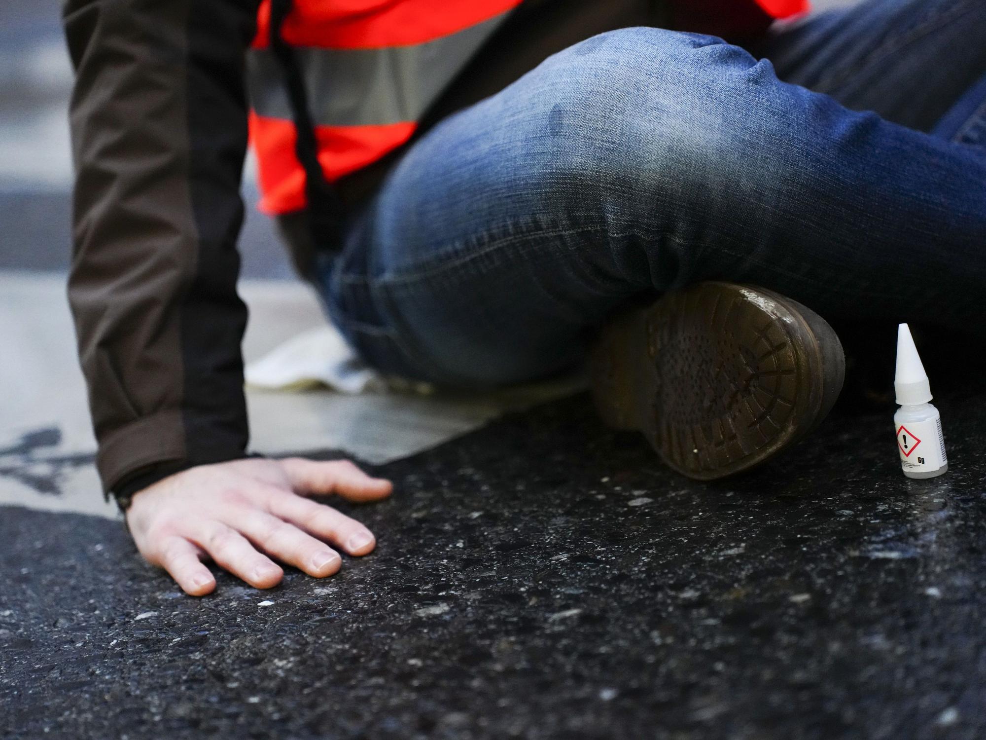 Ein Klimaaktivist der Gruppe „Letzte Generation“ klebt für eine Blockade auf einer Straße.
