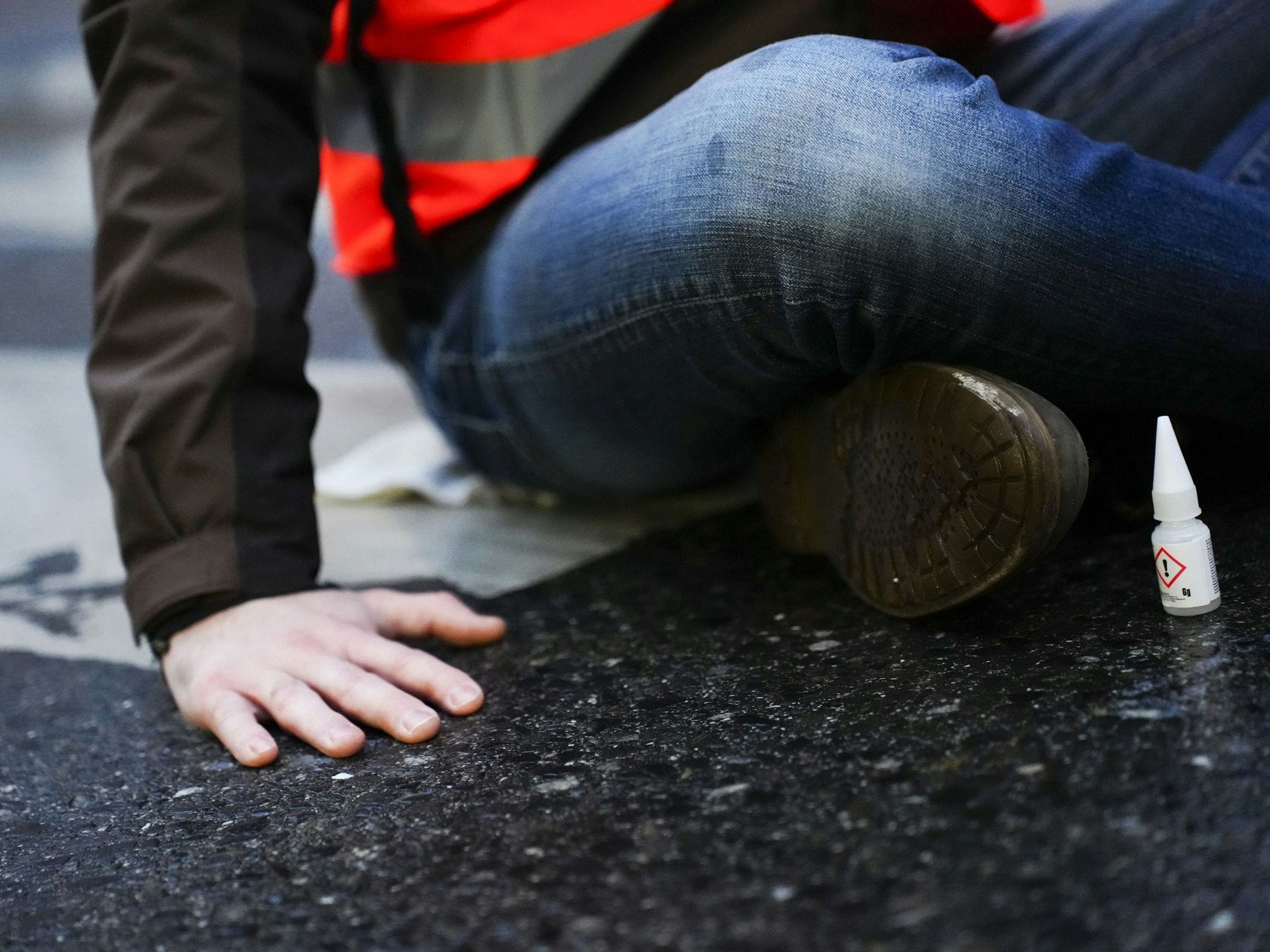 Ein Klimaaktivist der Gruppe „Letzte Generation“ klebt für eine Blockade auf einer Straße.