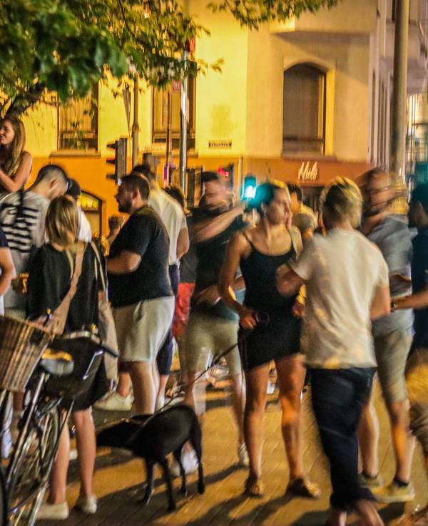 Menschen stehen auf der Venloer Straße in Köln und genießen das Nachtleben.