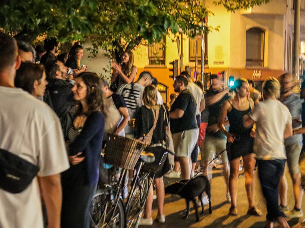 Menschen stehen auf der Venloer Straße in Köln und genießen das Nachtleben.