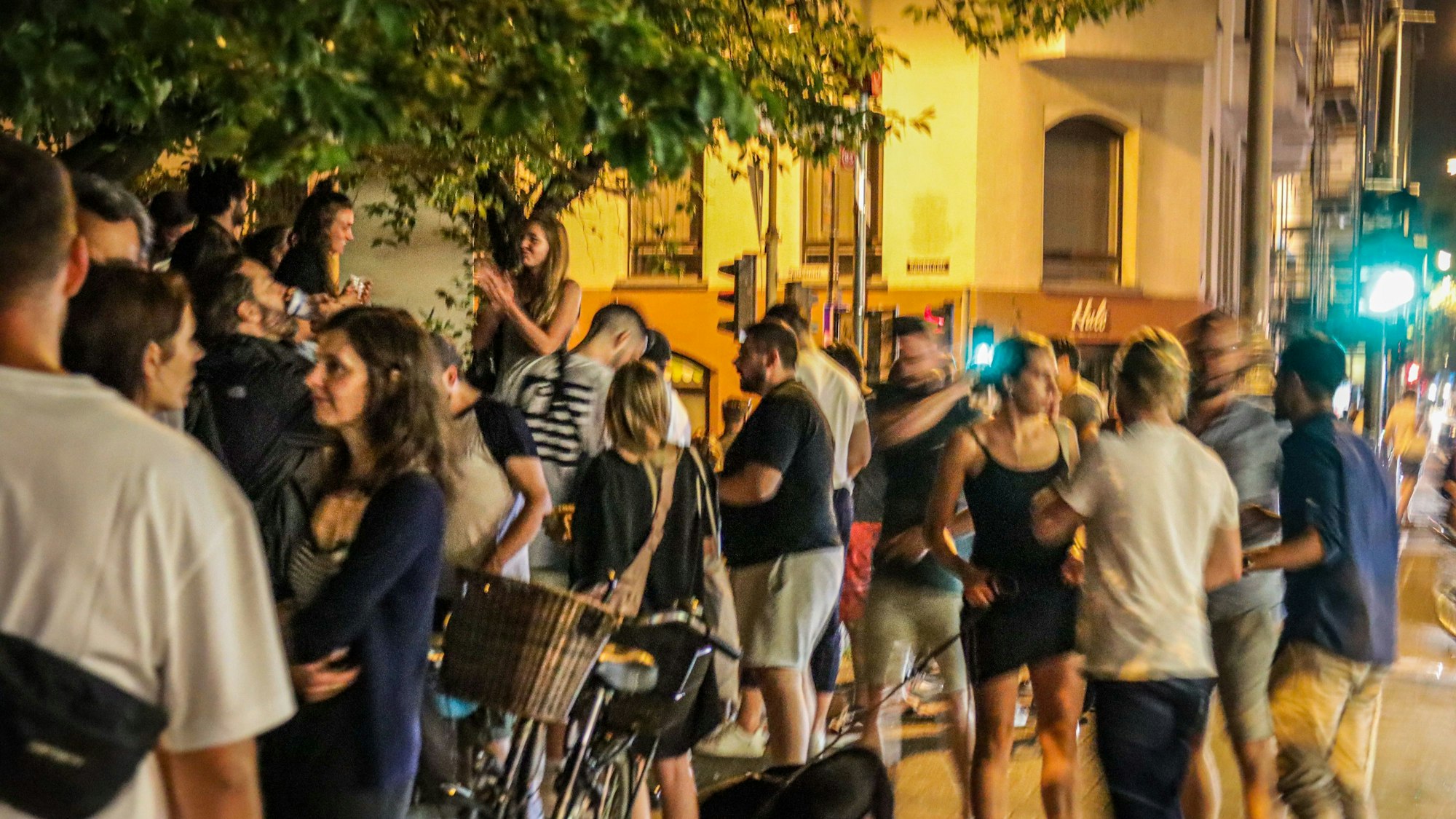 Menschen stehen auf der Venloer Straße in Köln und genießen das Nachtleben.