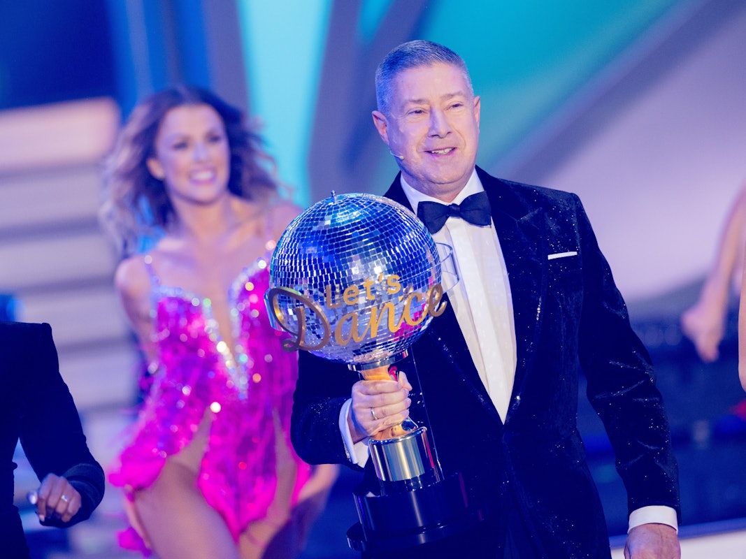 Joachim Llambi trägt einen Pokal.