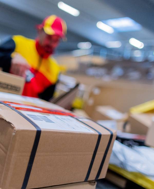 Ein DHL-Zusteller inmitten von Paketen.