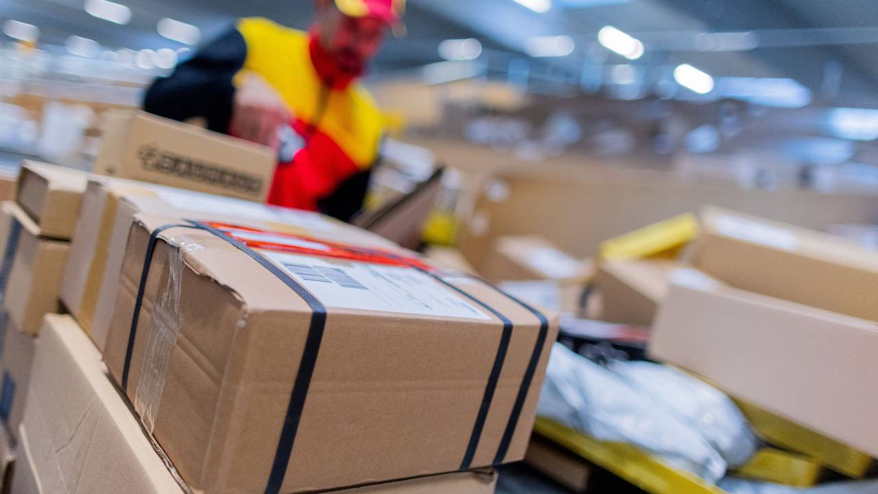 Ein DHL-Zusteller inmitten von Paketen.