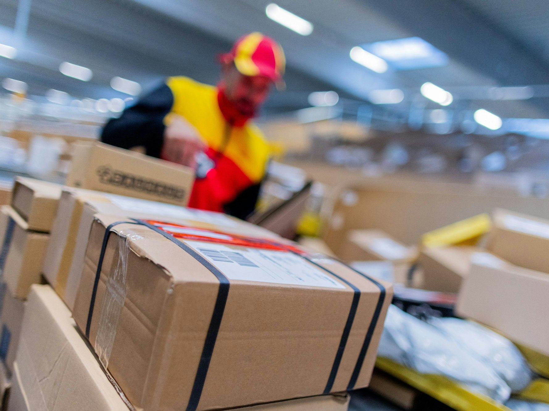 Ein DHL-Zusteller inmitten von Paketen.