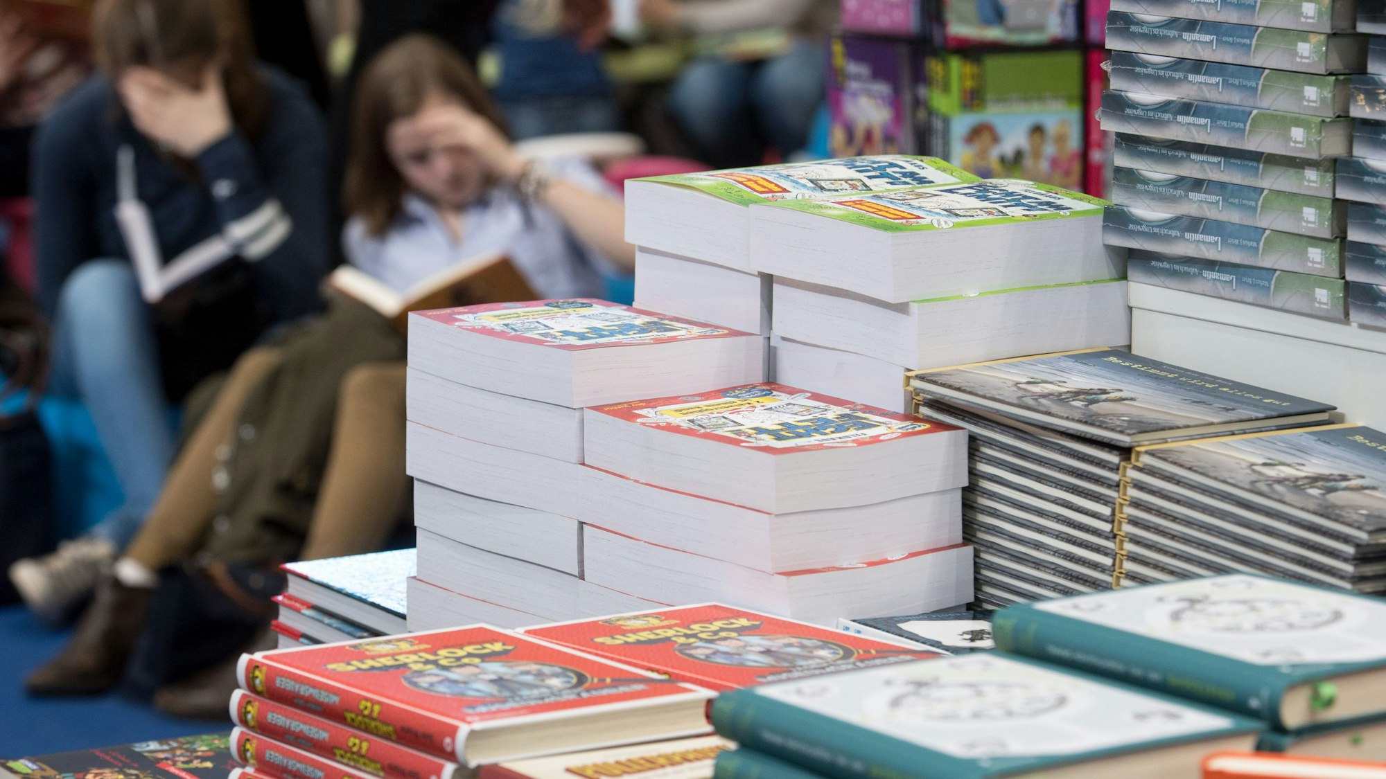 Jugendbücher liegen stapelweise auf einem Tisch.