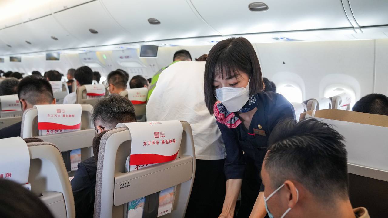 Eine Flugbegleiterin serviert einem Passagier an Bord eine Mahlzeit.