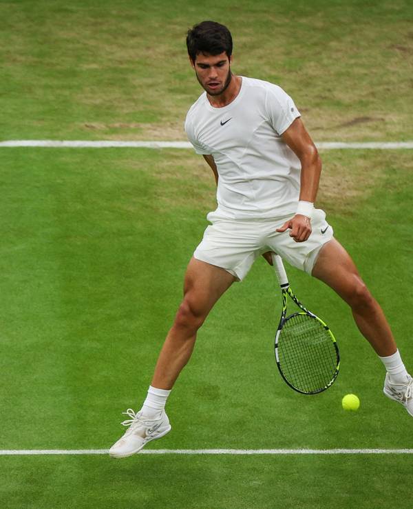 Carlos Alcaraz spielt den Ball mit seinem Schläger durch seine Beine.