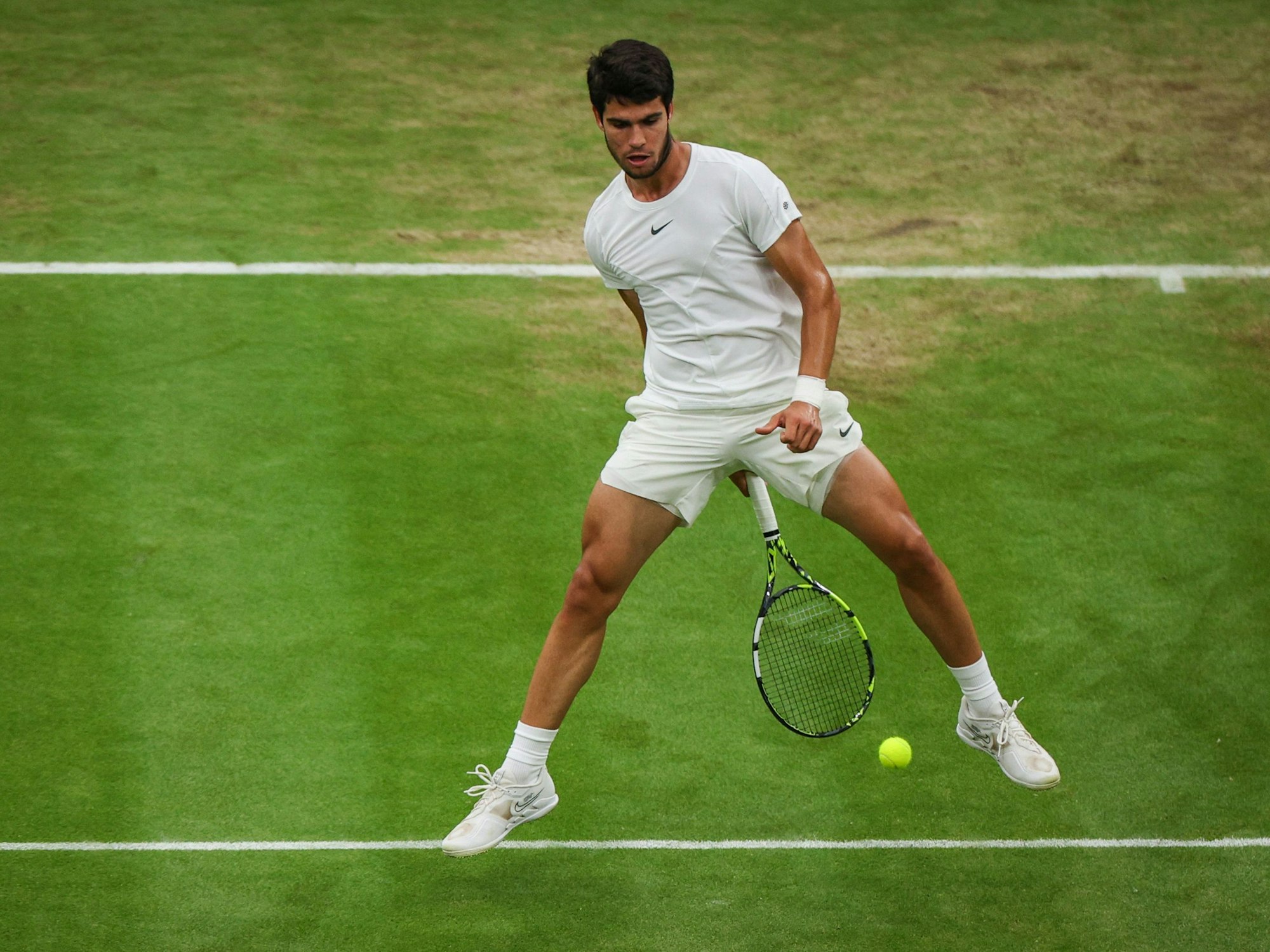 Carlos Alcaraz spielt den Ball mit seinem Schläger durch seine Beine.