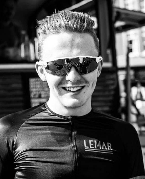 Connor Lambert lacht auf einem Schwarz-Weiß-Bild mit Sonnenbrille in die Kamera.