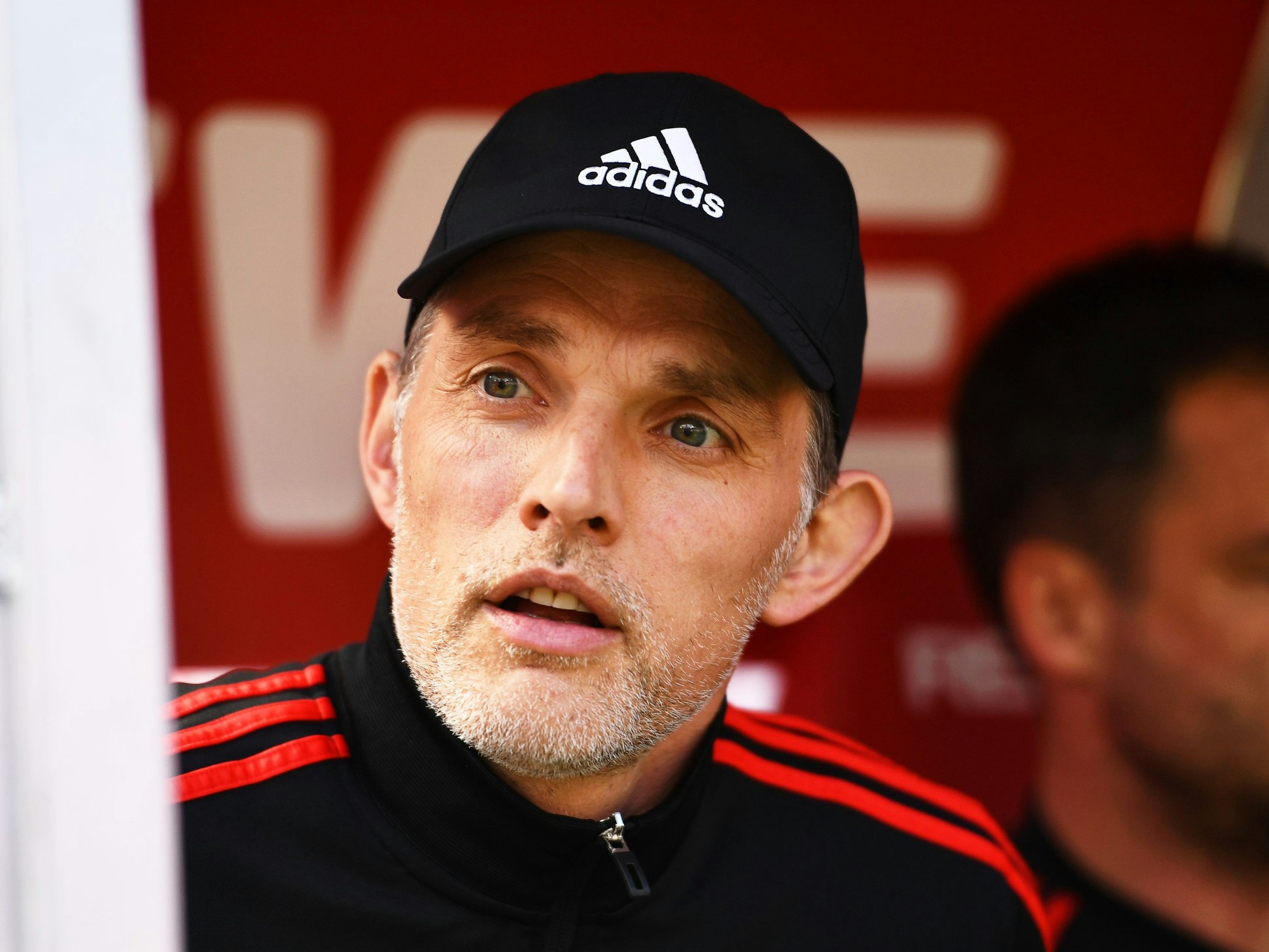 Thomas Tuchel sitzt auf er Bank. Er trägt eine schwarze Kappe.