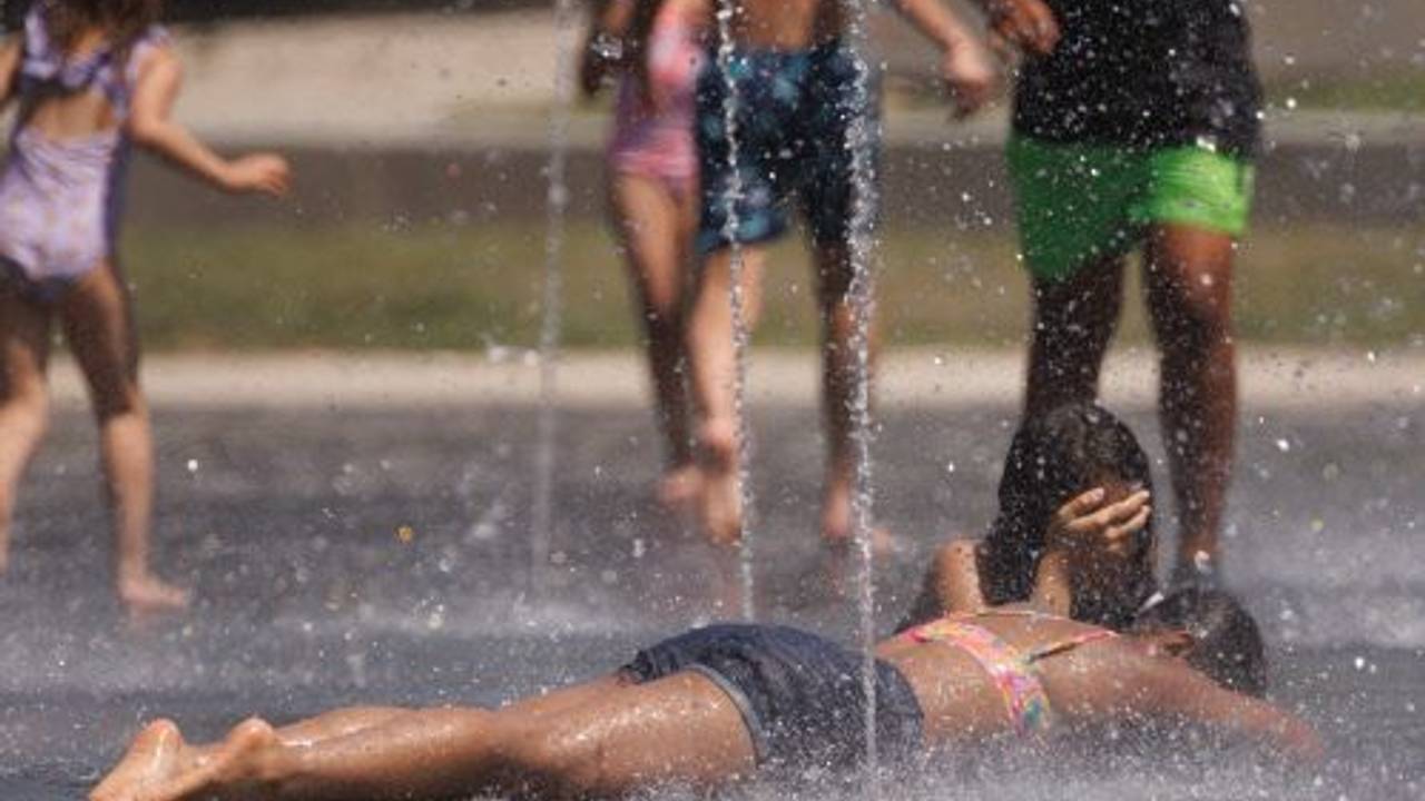 Kinder kühlen sich in einem Brunnen ab. Zu viel Hitze tut dem Körper nicht gut. Im Sommer sollten wir uns daher gut schützen.