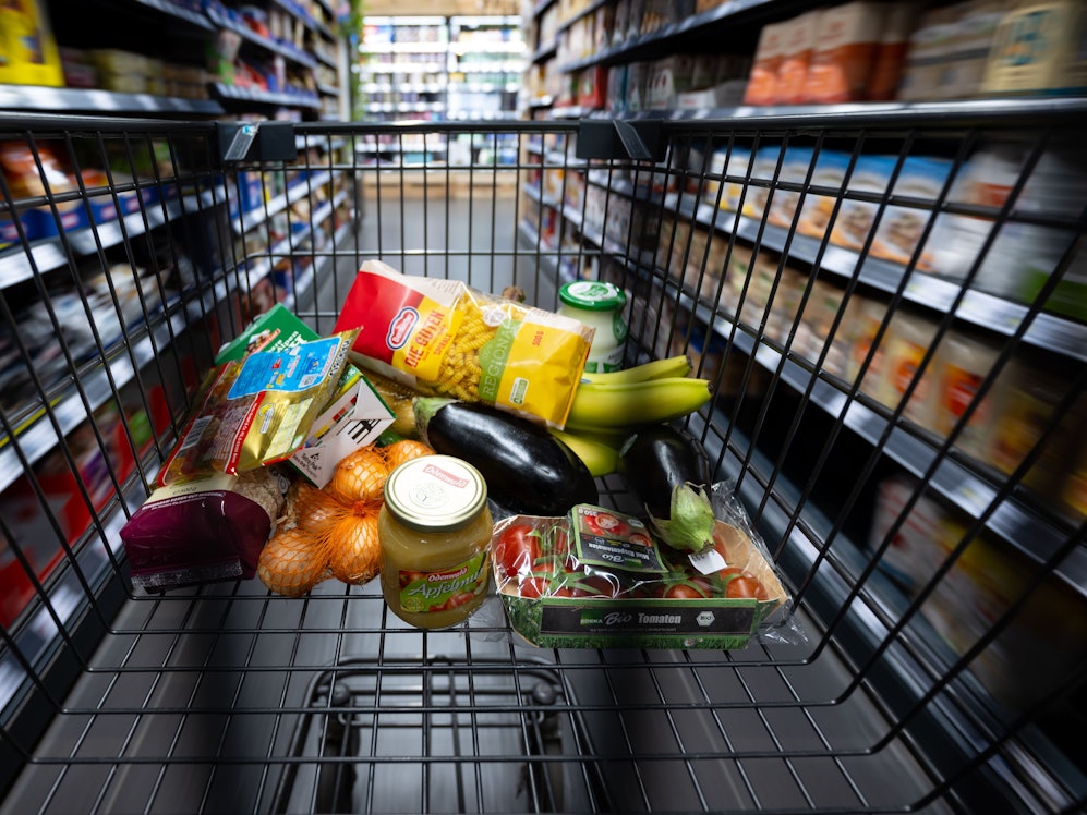 Verschiedene Lebensmittel liegen in einem Supermarkt in einem Einkaufswagen