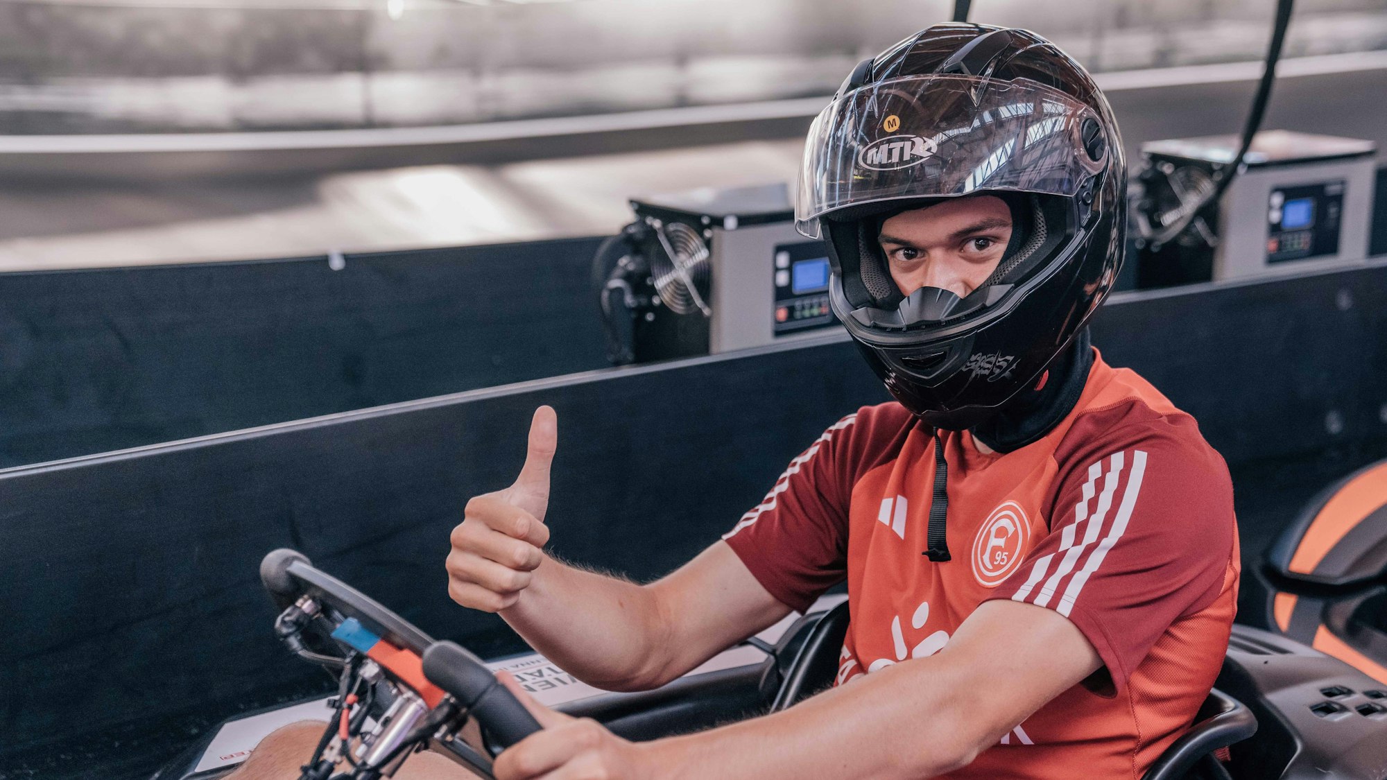 Ein Kart-Pilot hebt den Daumen hinter dem Steuer.