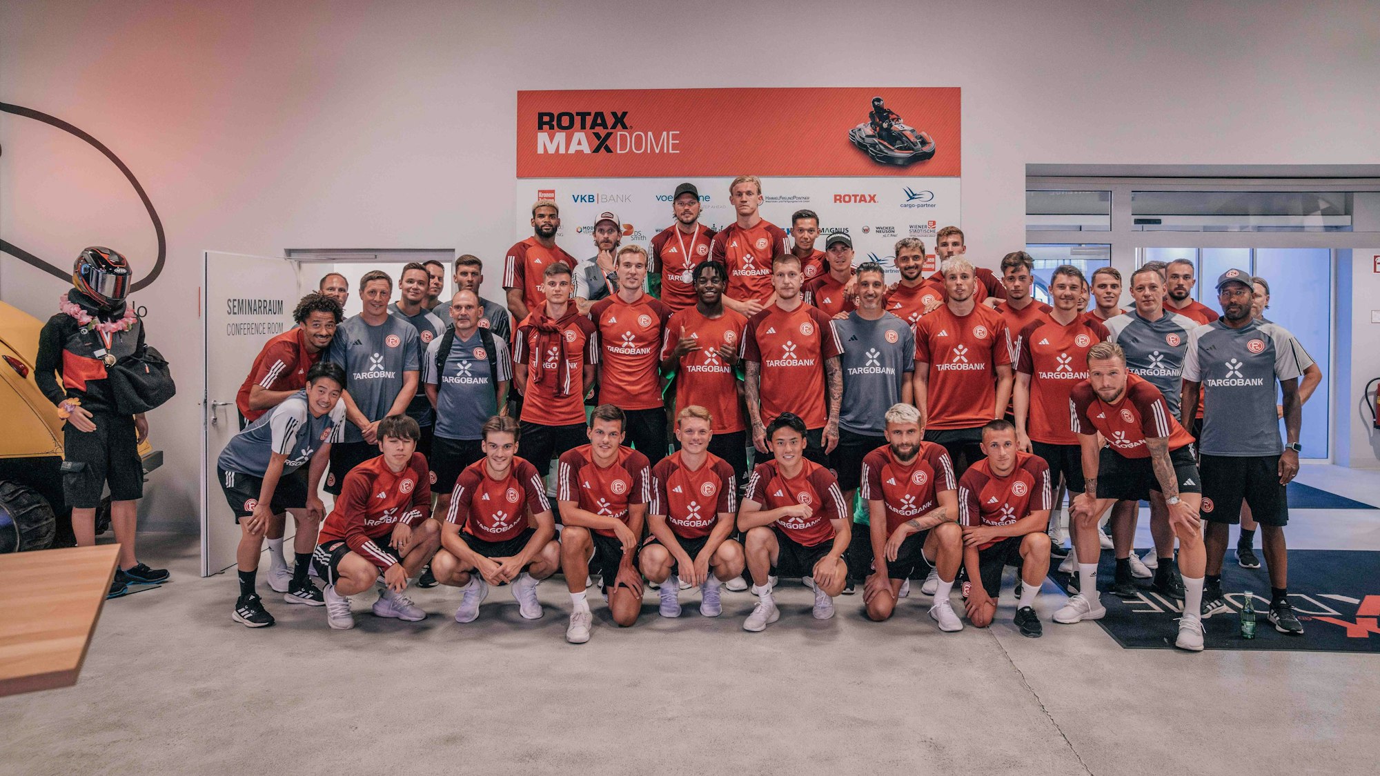 Die Profis von Fortuna Düsseldorf posieren auf der Kart-Bahn für ein Teamfoto.