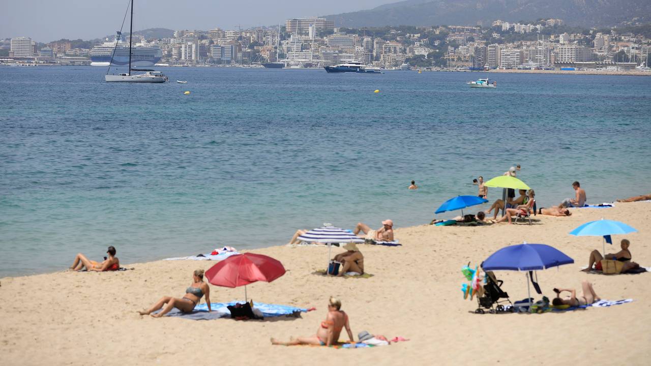 Menschen sonnen sich und benutzen Sonnenschirme am Strand.