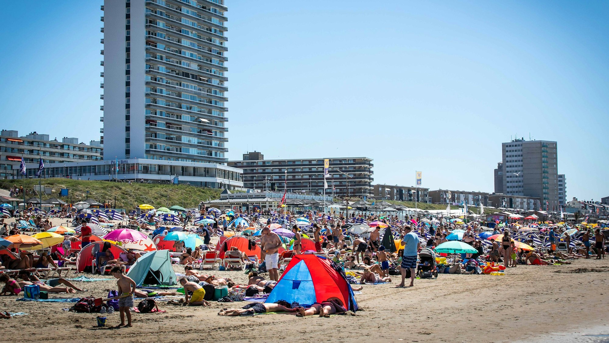 Zahlreiche Menschen genießen in unserem Archivbild (2020) das heiße Wetter am Strand nahe dem Bahnhof Zandvoort.