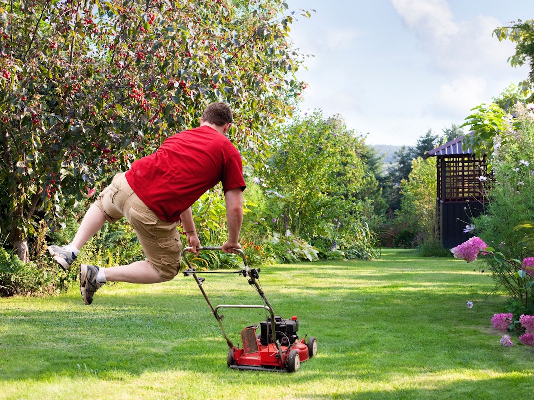 Mann hüpft beim Rasenmähen vor Freude in die Luft