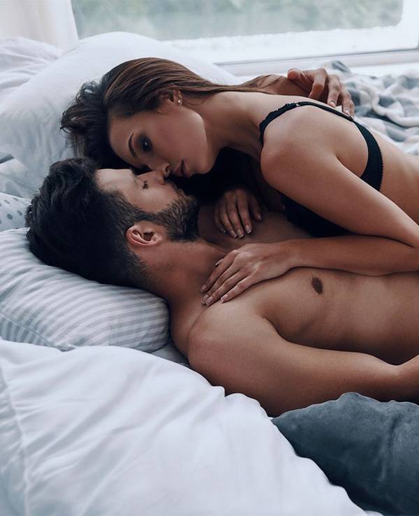 Mann und Frau liegen leicht bekleidet im Bett und halten sich erotisch in den Armen.