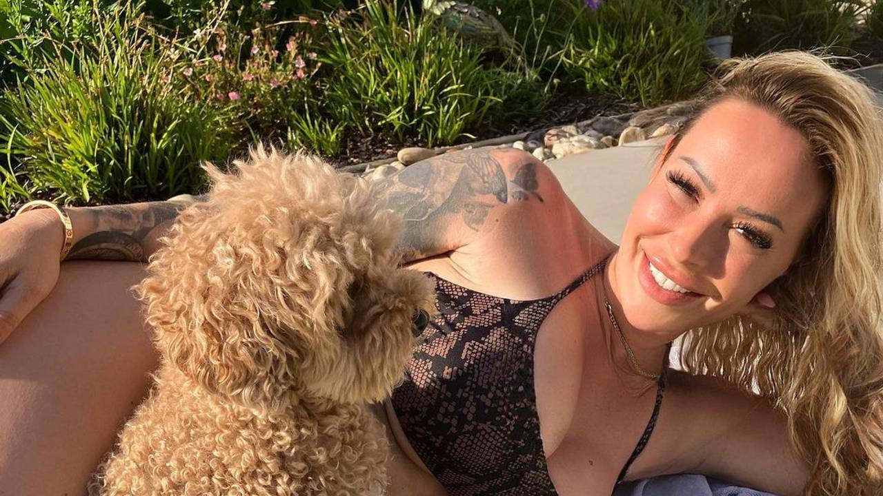 Cora Schumacher und ein Hund liegen gemeinsam auf einem Handtuch.