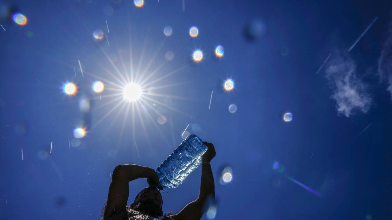 Ein Mann gießt sich kaltes Wasser über den Kopf, um sich an einem drückend heißen Tag abzukühlen.