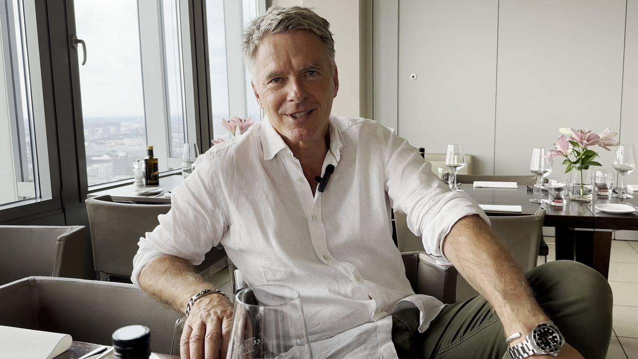 Jörg Pilawa sitzt an einem Tisch und lächelt in die Kamera.
