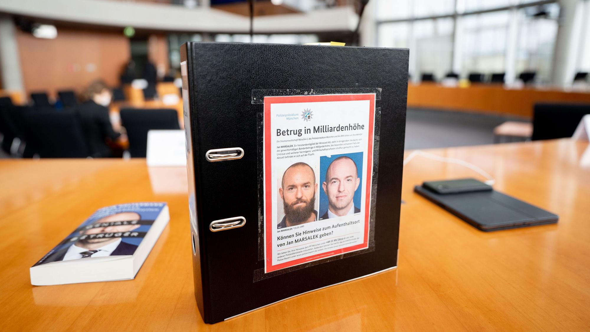 Der Aktenordner des ehemaligen Bundestagsabgeordneten de Masi (Die Linke) mit Fahndungsfotos des früheren Wirecard-Finanzvorstands Jan Marsalek ist im Sitzungssaal zum Bilanzskandal Wirecard im Paul-Löbe-Haus zu sehen.