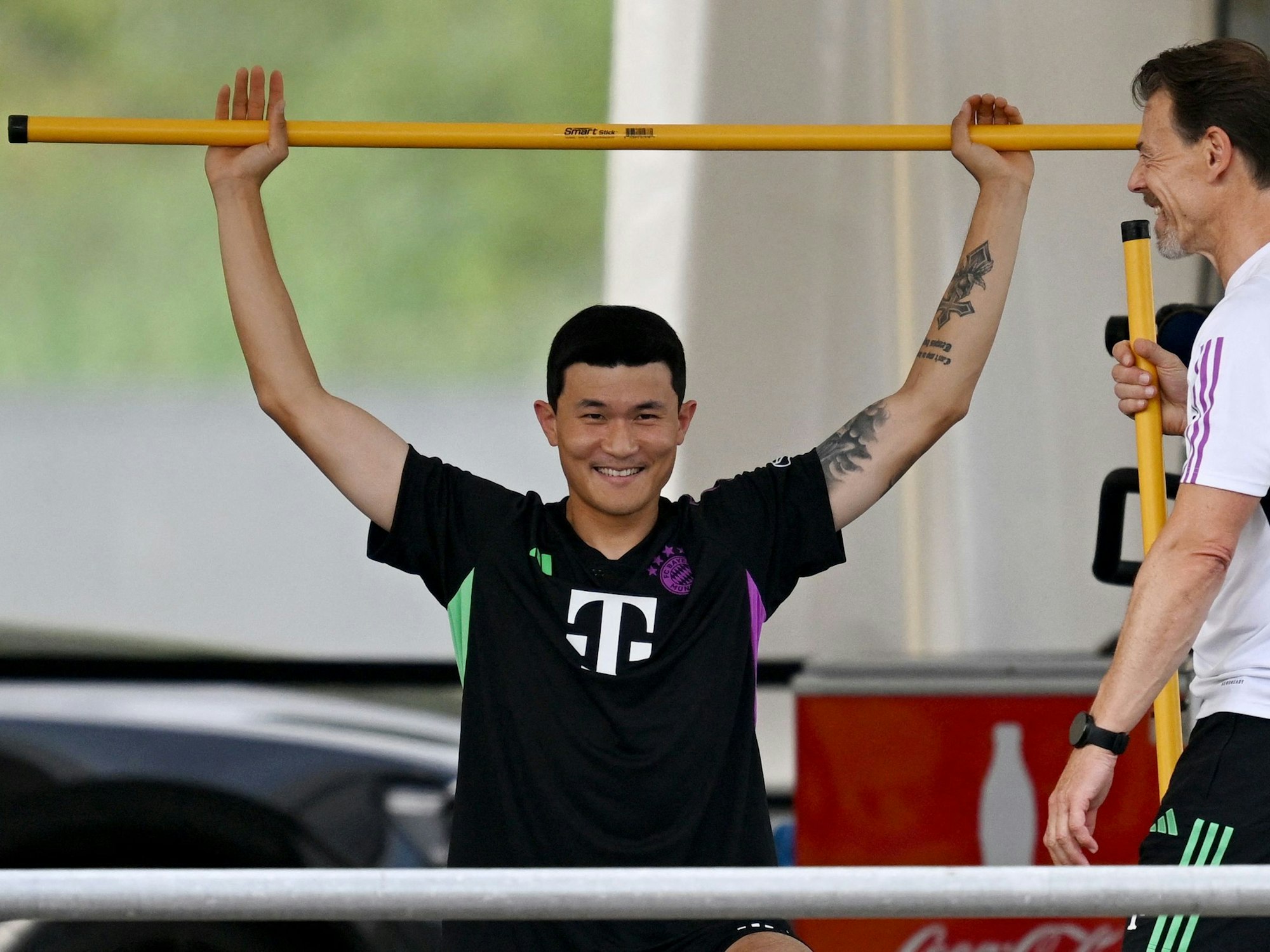 Min-jae Kim absolviert mithilfe einer Stange eine Stretching-Übung.