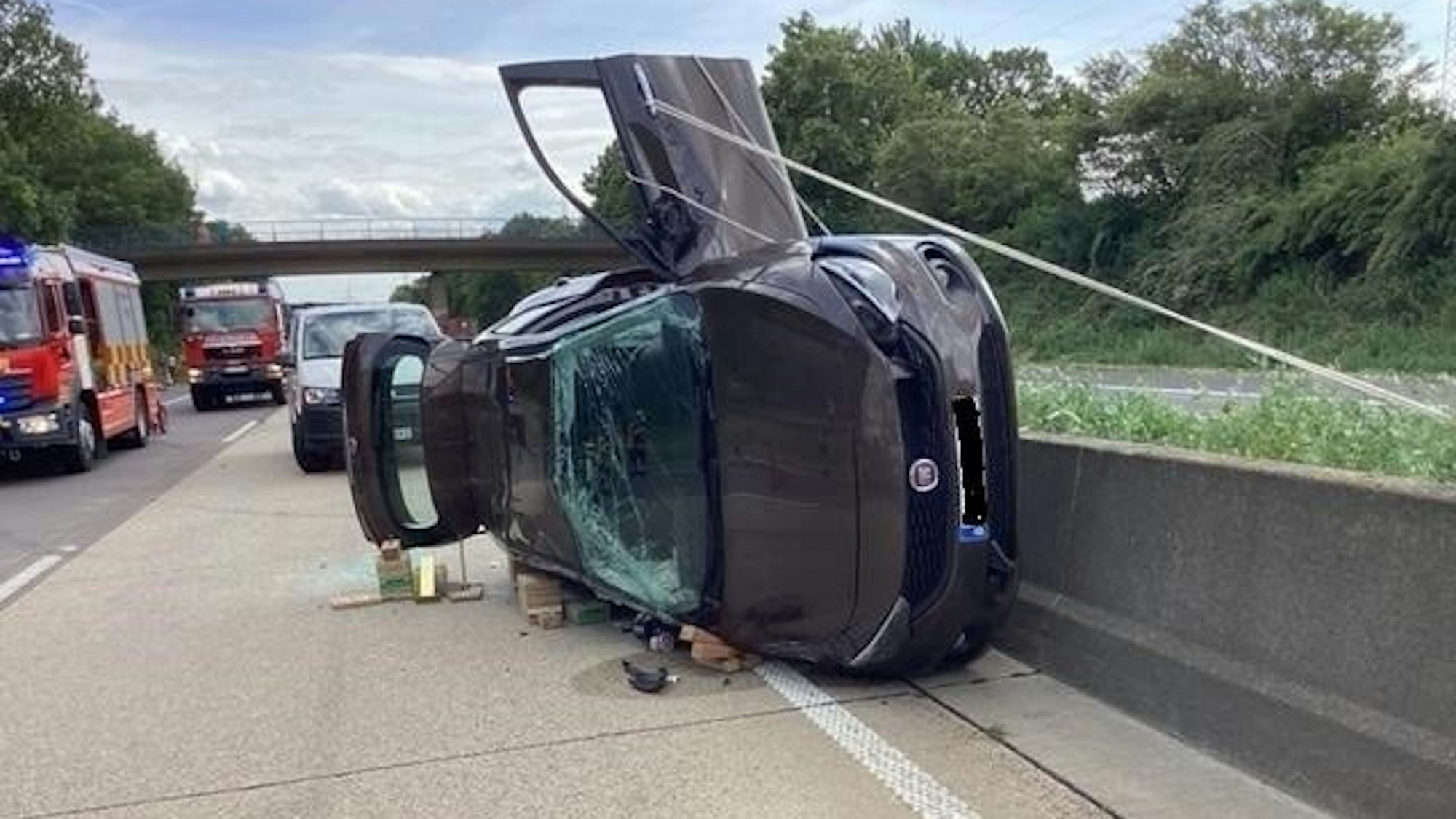 Ein Auto liegt nach einem Unfall auf der A61 auf der Seite, direkt an der mittleren Leitplanke.