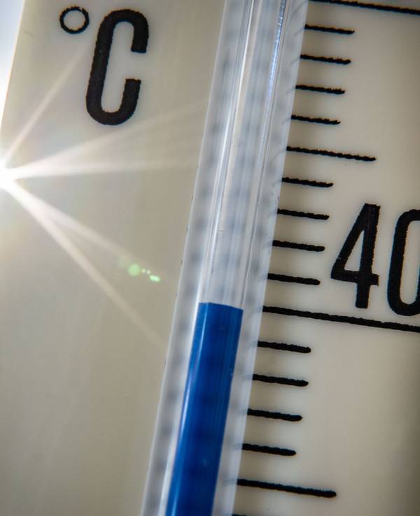 Ein Außenthermometer zeigt vor dem blauen Himmel und der Sonne eine Temperatur von nahezu 40 Grad Celsius an, hier im Juli 2022 in Frankfurt am Main.