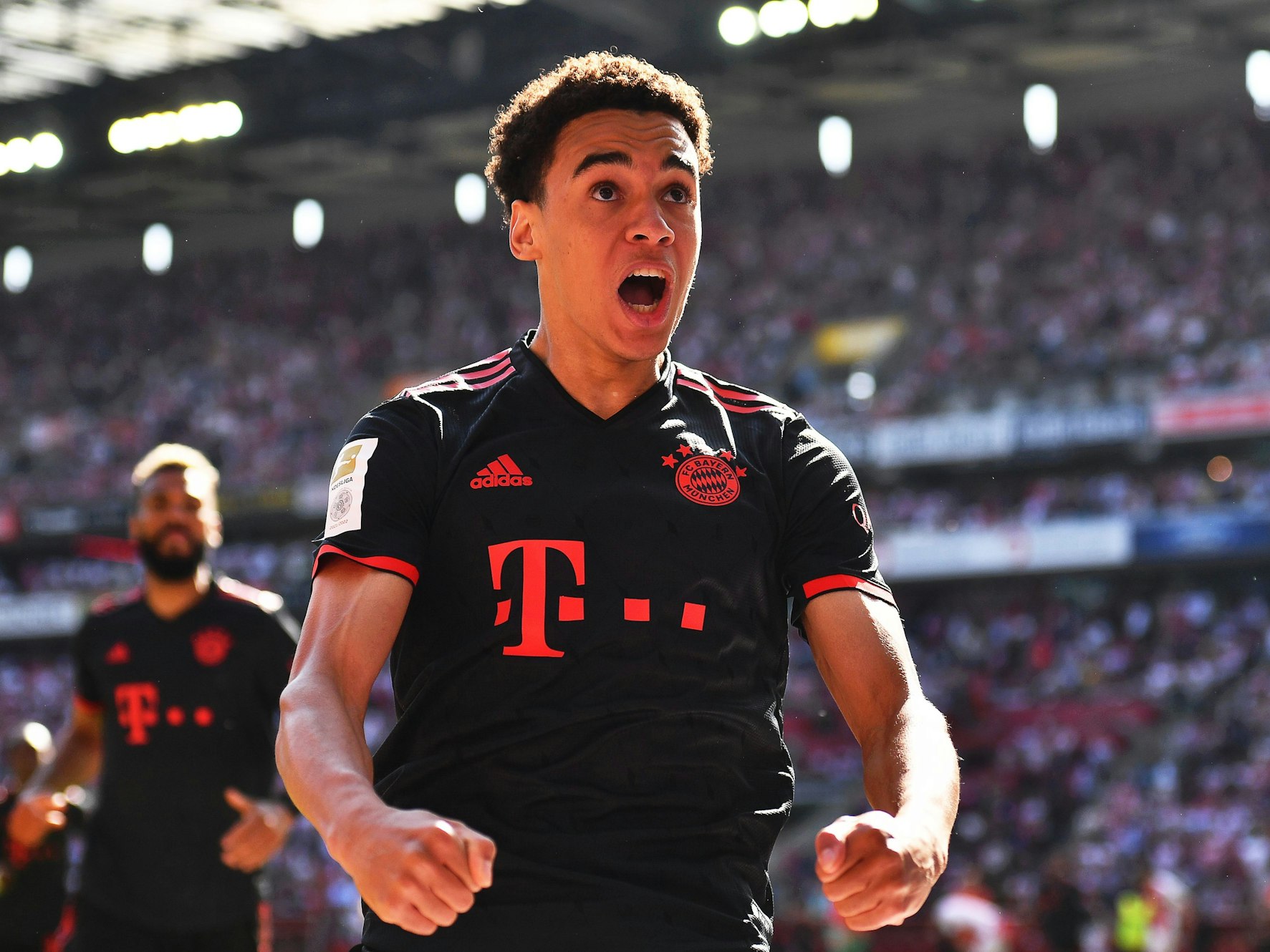 Jamal Musiala, im schwarzen Bayern-Trikot, reißt den Mund auf und ballt beide Fäuste vor seinem Körper.