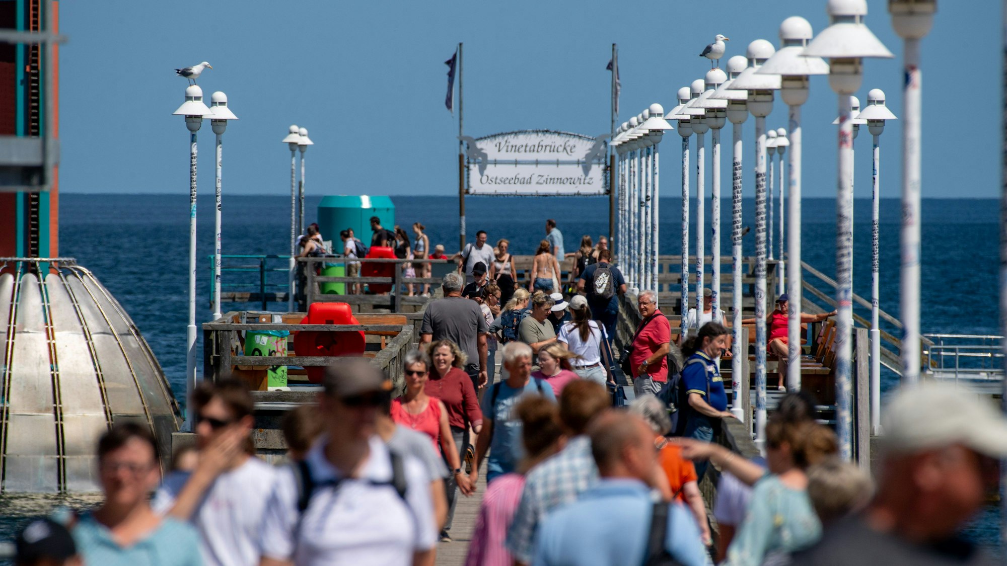 Touristen gehen bei sonnigem Wetter über die Seebrücke am Strand der Insel.