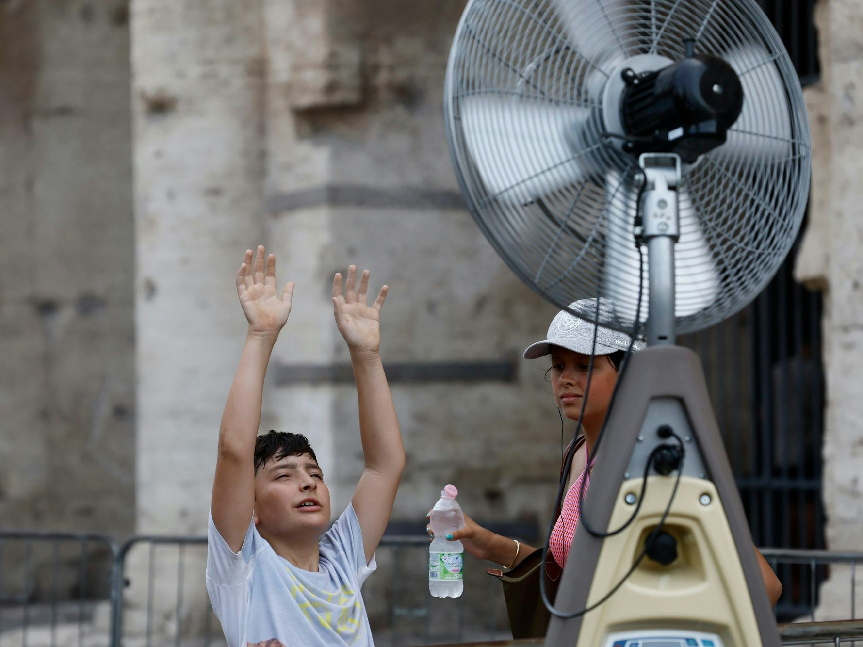 Ein Junge kühlt sich vor einem Ventilator in der Nähe des Kolosseums ab.