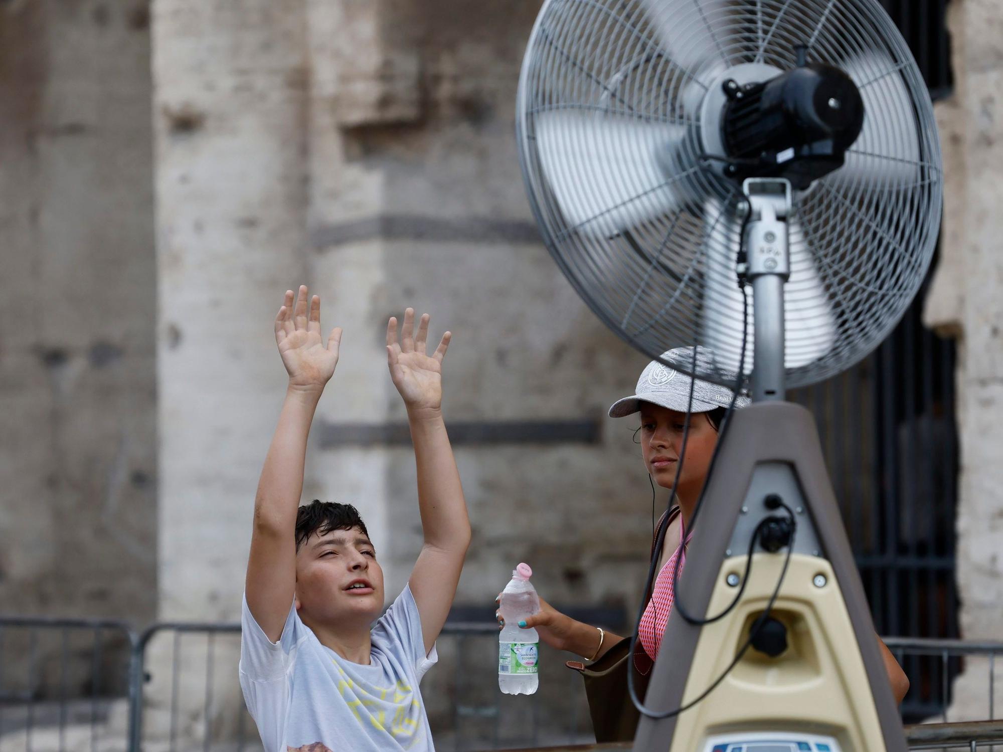 Ein Junge kühlt sich vor einem Ventilator in der Nähe des Kolosseums ab.