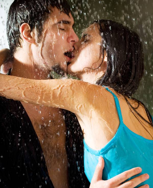 Young happy amorous couple hugging and kissing under a rain, outdoors
