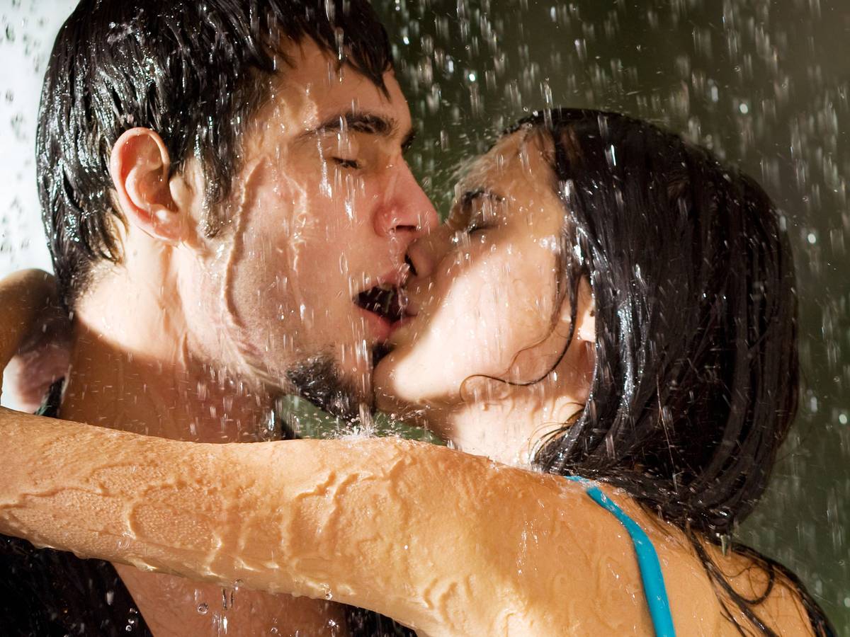 Young happy amorous couple hugging and kissing under a rain, outdoors